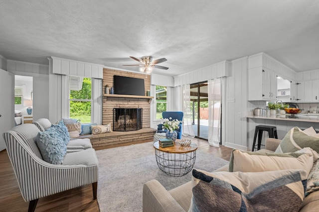 living room featuring dark hardwood / wood-style floors, ceiling fan, and a fireplace