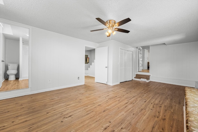 unfurnished living room with ceiling fan, light hardwood / wood-style flooring, and a textured ceiling