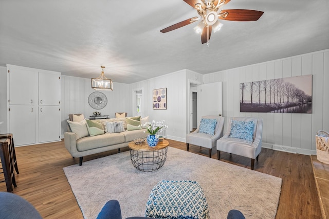 living room featuring ceiling fan with notable chandelier and hardwood / wood-style flooring