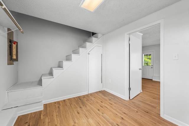 stairway with hardwood / wood-style floors and a textured ceiling