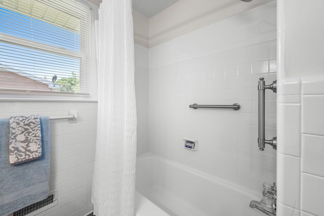 bathroom with shower / bathtub combination with curtain and tile walls