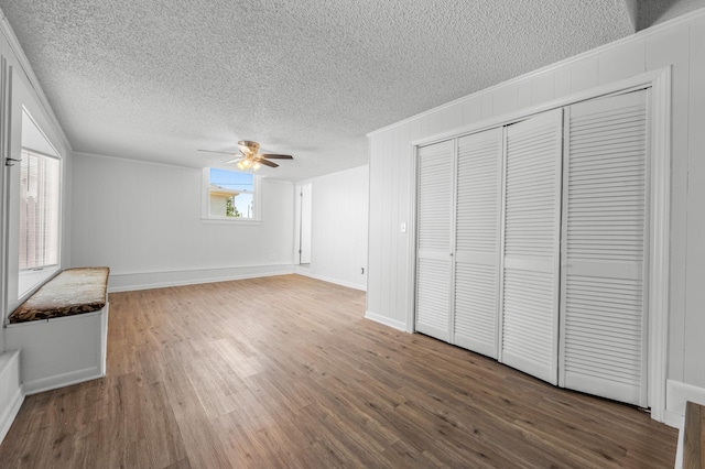 unfurnished bedroom featuring ceiling fan, dark hardwood / wood-style flooring, wood walls, and a textured ceiling