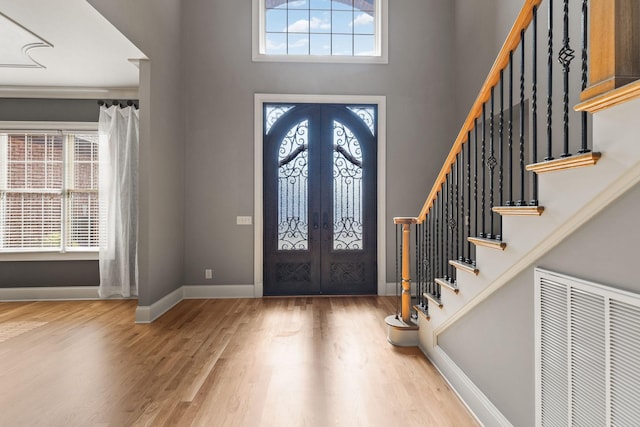 foyer entrance with hardwood / wood-style flooring, a high ceiling, and french doors