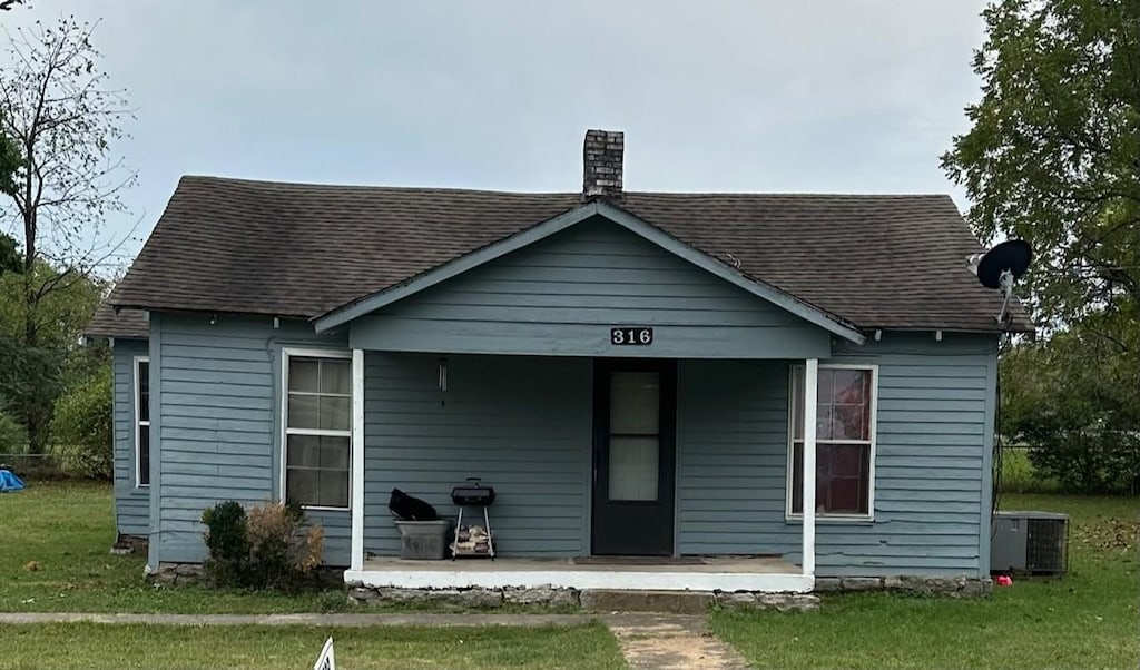 view of front facade featuring a front yard, central AC unit, and covered porch