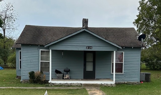 view of front of home with cooling unit, a front lawn, and a porch