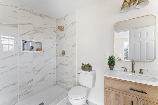 bathroom with tiled shower, vanity, and toilet