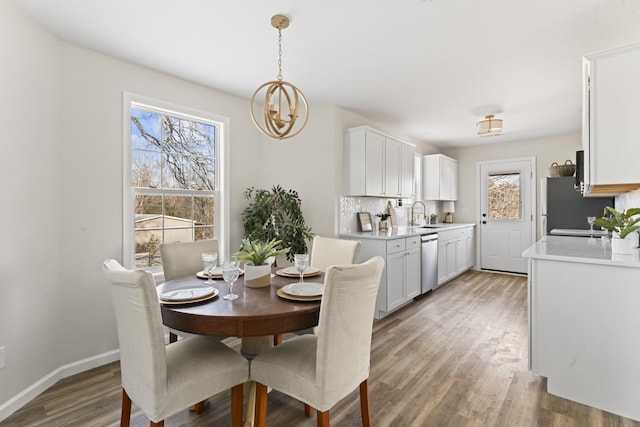 dining space with sink, an inviting chandelier, and hardwood / wood-style flooring