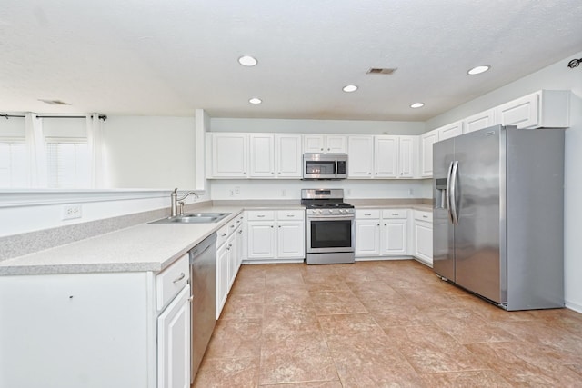 kitchen with a textured ceiling, sink, white cabinetry, and stainless steel appliances