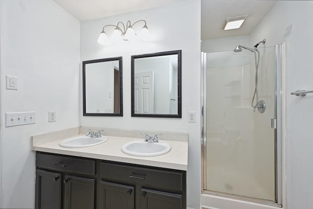 bathroom with vanity, a textured ceiling, and a shower with door