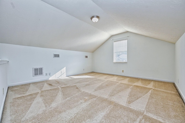 bonus room with a textured ceiling, light colored carpet, and vaulted ceiling