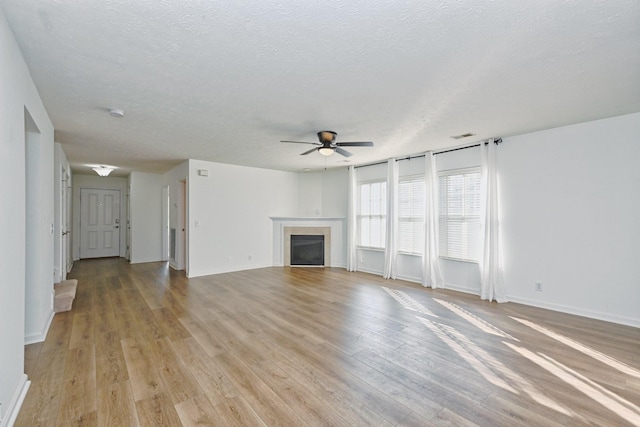 unfurnished living room featuring ceiling fan, light hardwood / wood-style flooring, and a textured ceiling