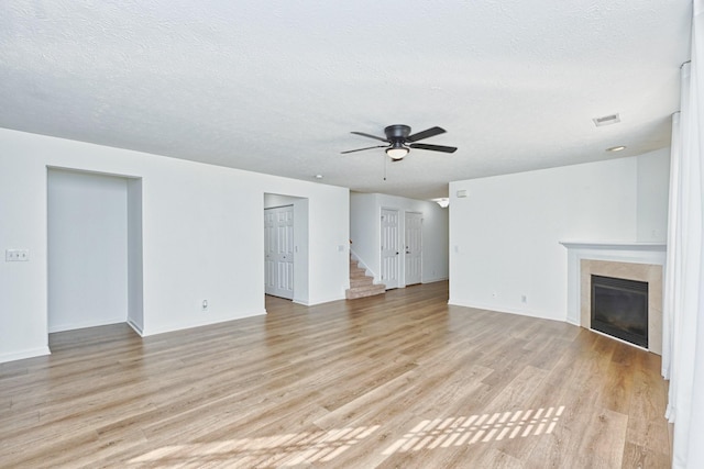 unfurnished living room featuring ceiling fan, light hardwood / wood-style floors, and a textured ceiling