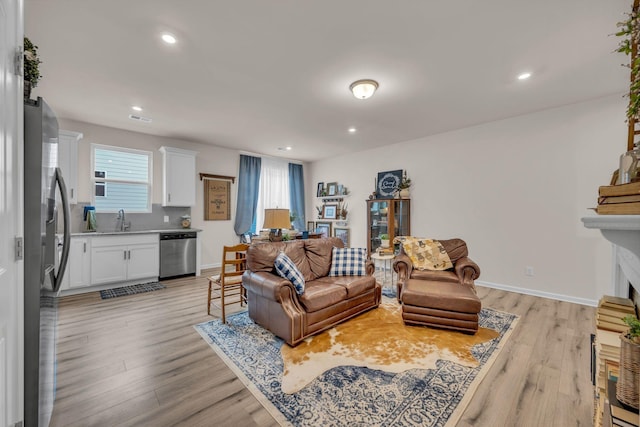 living room with a fireplace, light hardwood / wood-style floors, and sink