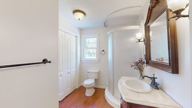 bathroom with hardwood / wood-style floors, vanity, a textured ceiling, and toilet