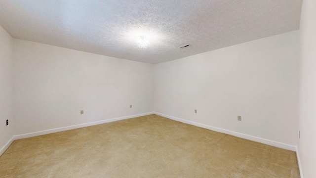 spare room featuring light colored carpet and a textured ceiling