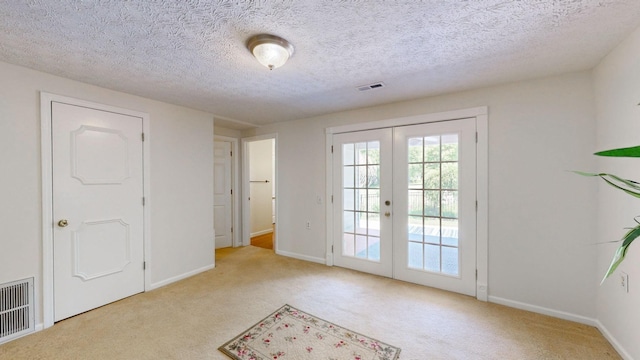 doorway to outside featuring light carpet, french doors, and a textured ceiling