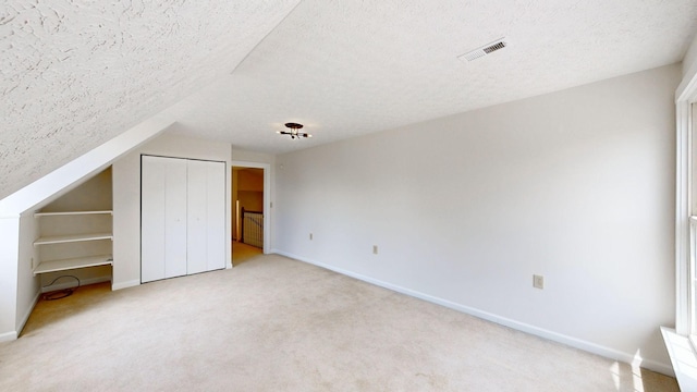 additional living space featuring lofted ceiling, carpet, and a textured ceiling