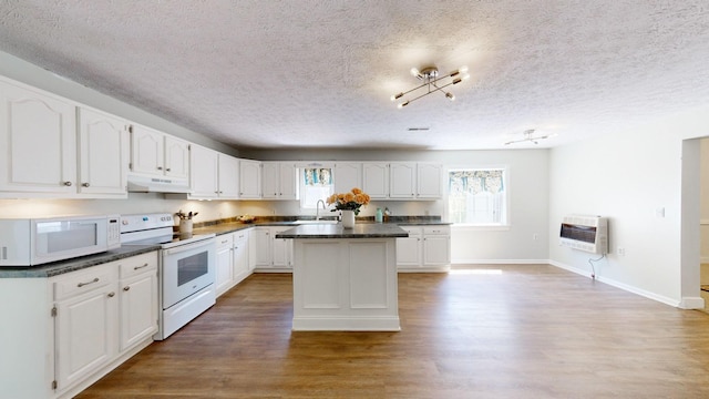 kitchen with white cabinets, white appliances, heating unit, and a kitchen island