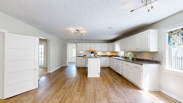 kitchen featuring sink, white cabinets, a healthy amount of sunlight, and white appliances