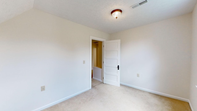 carpeted spare room with a textured ceiling and lofted ceiling