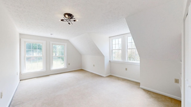 additional living space featuring a textured ceiling, light colored carpet, and lofted ceiling