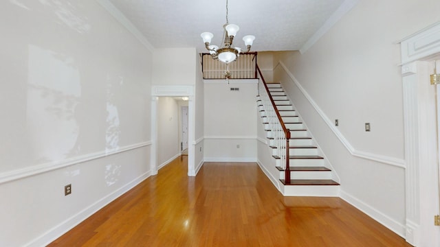 stairway featuring ornamental molding, a chandelier, a textured ceiling, and hardwood / wood-style flooring