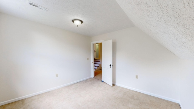 bonus room featuring vaulted ceiling, light carpet, and a textured ceiling