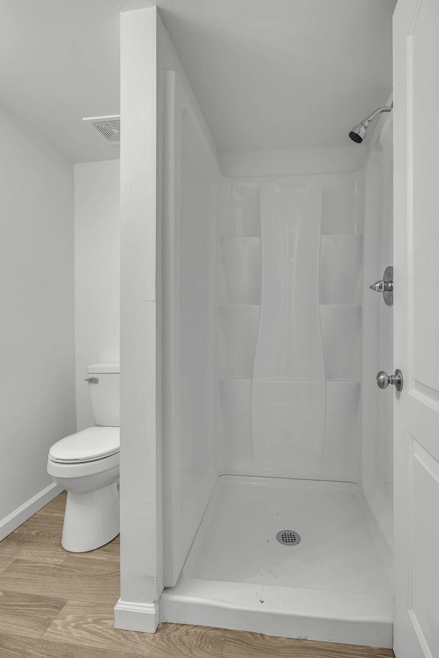 bathroom featuring a shower, hardwood / wood-style flooring, and toilet