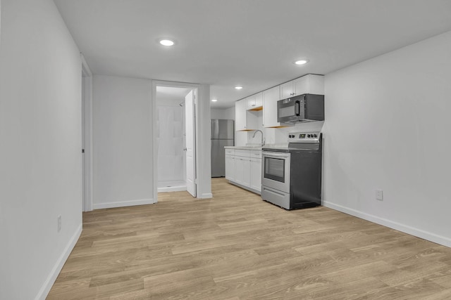 kitchen with sink, white cabinetry, stainless steel appliances, and light hardwood / wood-style flooring