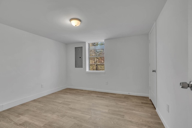 unfurnished room featuring electric panel and light hardwood / wood-style flooring