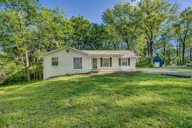 ranch-style house featuring covered porch, a garage, a front lawn, and an outdoor structure