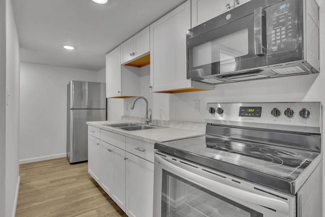 kitchen with white cabinets, light wood-type flooring, sink, and appliances with stainless steel finishes