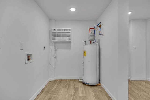 clothes washing area featuring washer hookup, a wall mounted air conditioner, electric dryer hookup, water heater, and light hardwood / wood-style floors