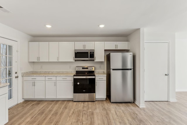 kitchen with white cabinets, stainless steel appliances, and light hardwood / wood-style flooring