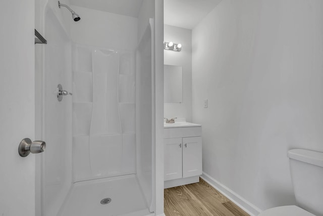 bathroom with hardwood / wood-style floors, toilet, a shower, and vanity