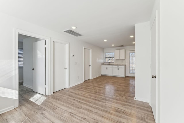 unfurnished living room with light hardwood / wood-style floors and sink