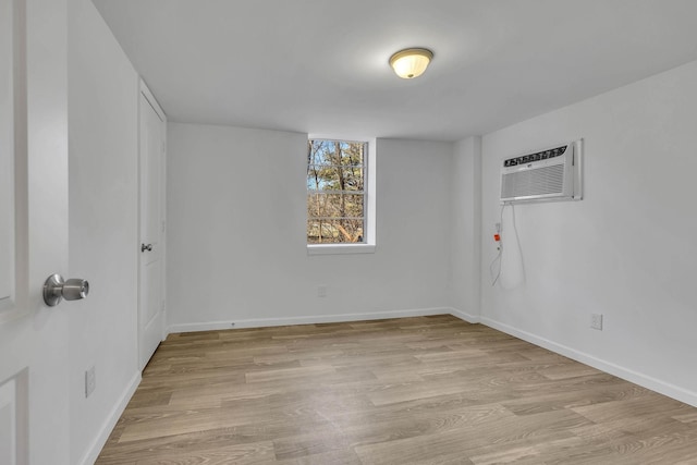 empty room with a wall mounted air conditioner and light wood-type flooring