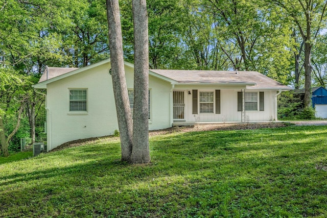 ranch-style home featuring a porch, cooling unit, and a front yard