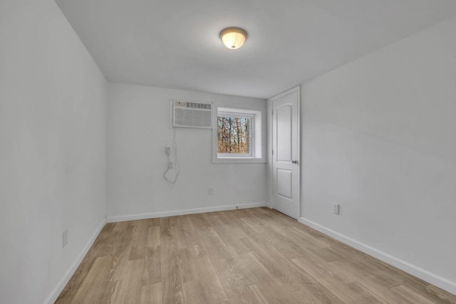 unfurnished room featuring a wall unit AC and light hardwood / wood-style flooring