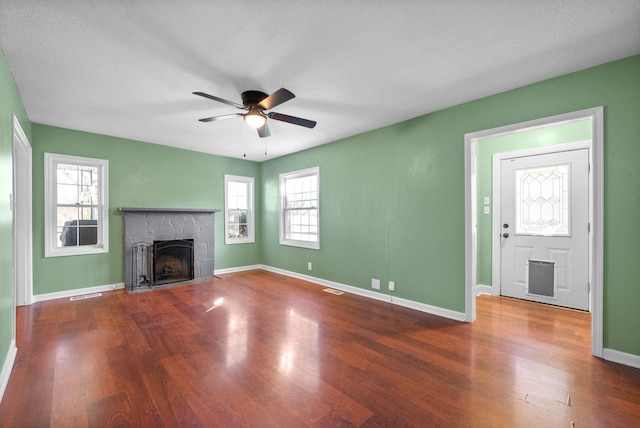 unfurnished living room featuring ceiling fan, a textured ceiling, wood-type flooring, and a fireplace