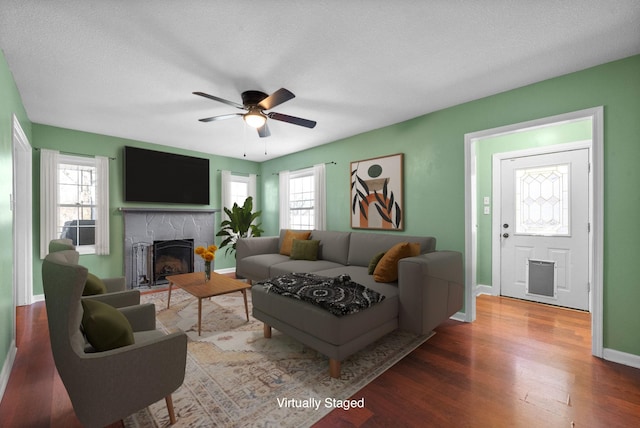 living room with ceiling fan, a textured ceiling, and hardwood / wood-style flooring