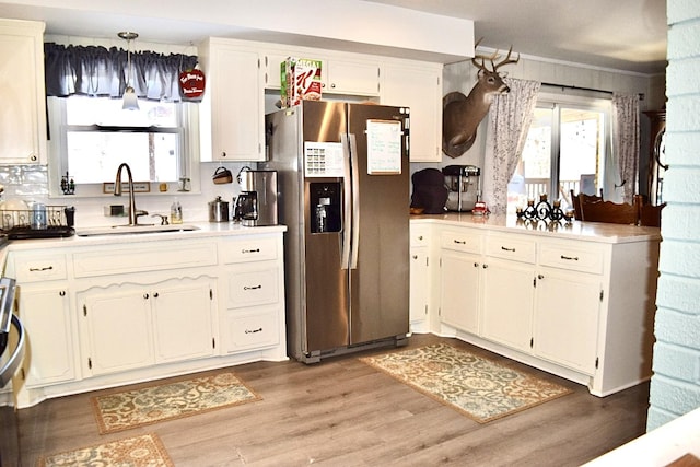 kitchen featuring stainless steel refrigerator with ice dispenser, sink, a healthy amount of sunlight, and light wood-type flooring