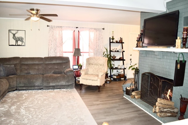 living room featuring wood-type flooring, a brick fireplace, and ceiling fan