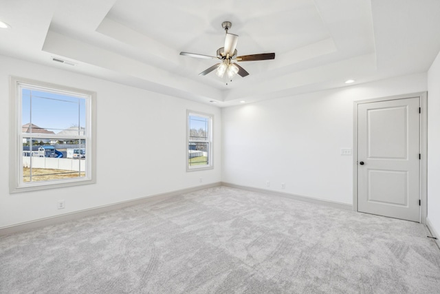 carpeted empty room featuring a raised ceiling and ceiling fan