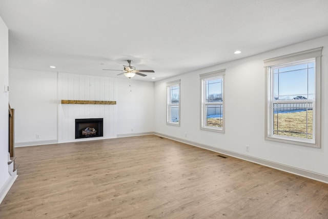 unfurnished living room with plenty of natural light, ceiling fan, a fireplace, and light hardwood / wood-style flooring