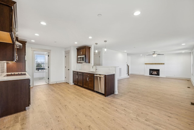 kitchen featuring pendant lighting, sink, light hardwood / wood-style flooring, ceiling fan, and stainless steel appliances