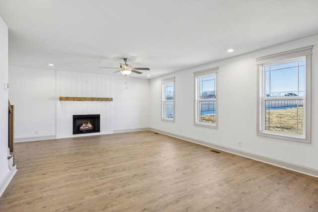 unfurnished living room featuring a large fireplace, light hardwood / wood-style floors, and plenty of natural light