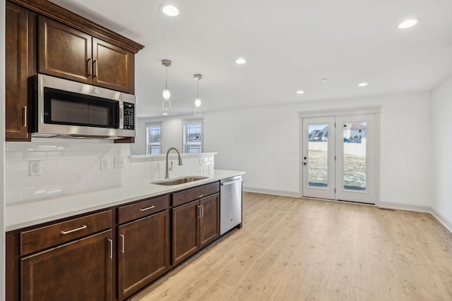 kitchen featuring sink, hanging light fixtures, a healthy amount of sunlight, stainless steel appliances, and decorative backsplash