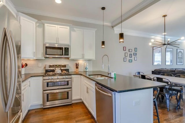 kitchen featuring kitchen peninsula, appliances with stainless steel finishes, sink, decorative light fixtures, and white cabinets