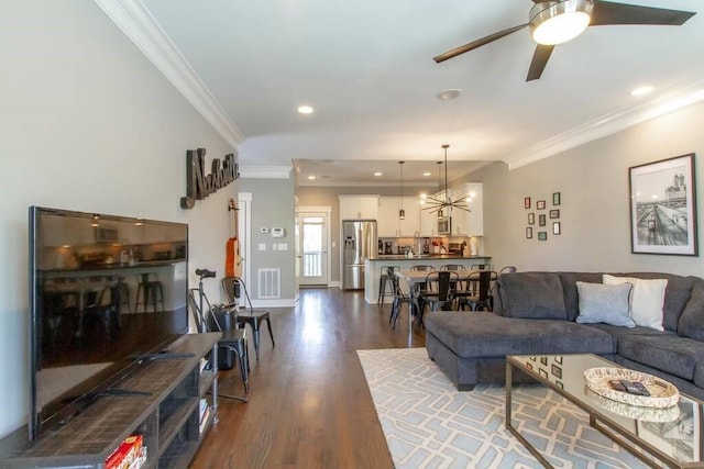 living room with ceiling fan with notable chandelier, dark wood-type flooring, and crown molding